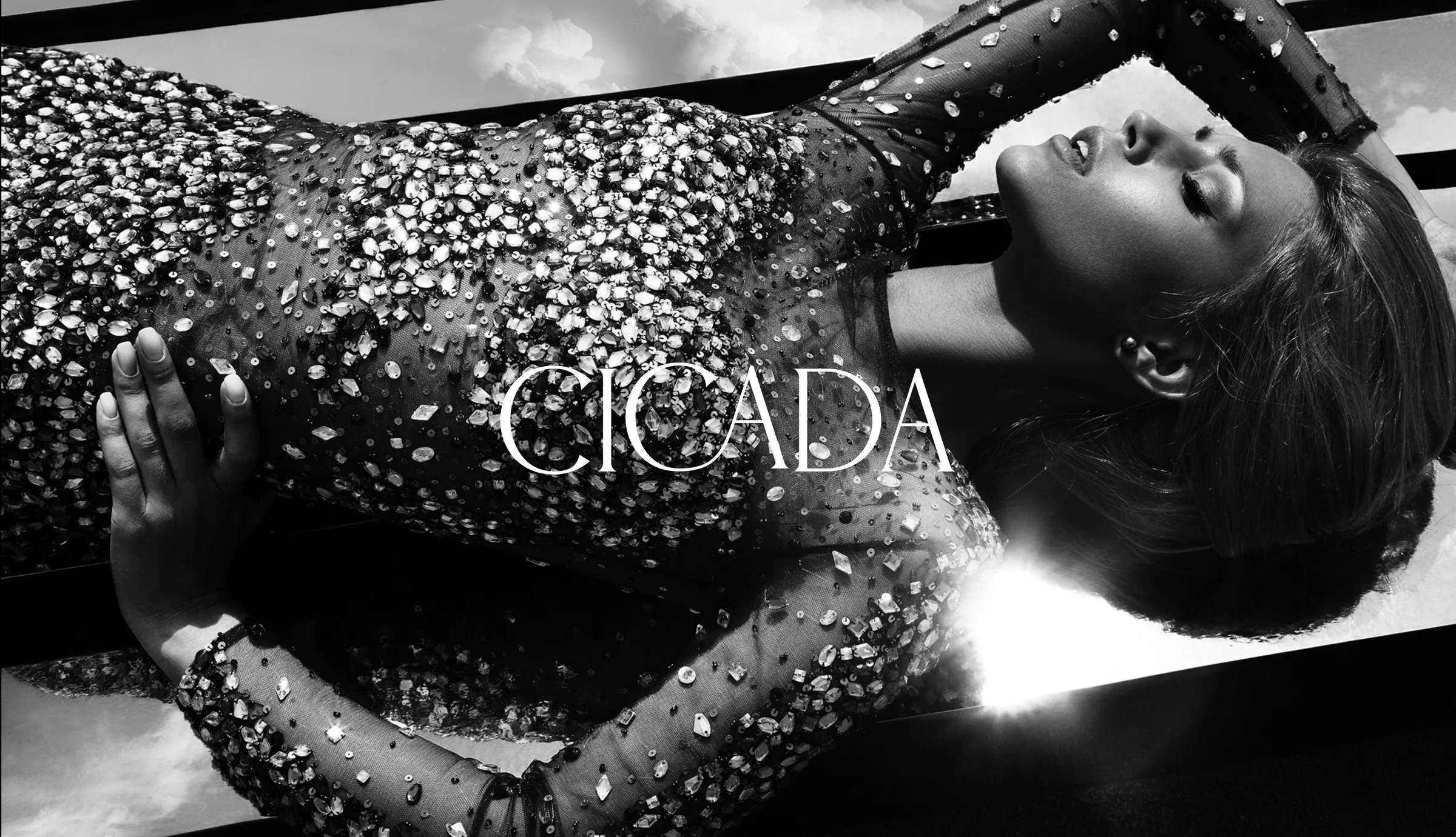 The CICADA wordmark set over a black-and-white campaign photograph of a model in a jewel-embellished gown