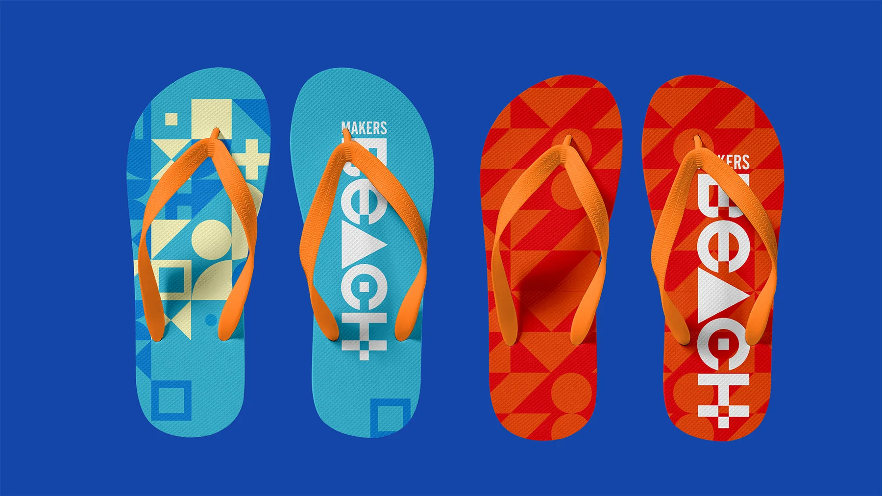 Two pairs of Makers Beach flip-flops in blue and red, each printed with the pattern system and wordmark